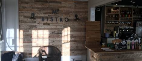 A bistro with a wooden wall and a bar area with various bottles and glasses.