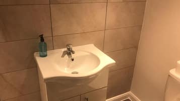 Un baño con lavamanos blanco, espejo e inodoro.