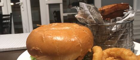 A plate with a burger, onion rings, and a piece of fried chicken.