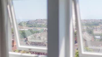 Une vue à travers une fenêtre, avec un ciel dégagé, un paysage lointain et des bâtiments.