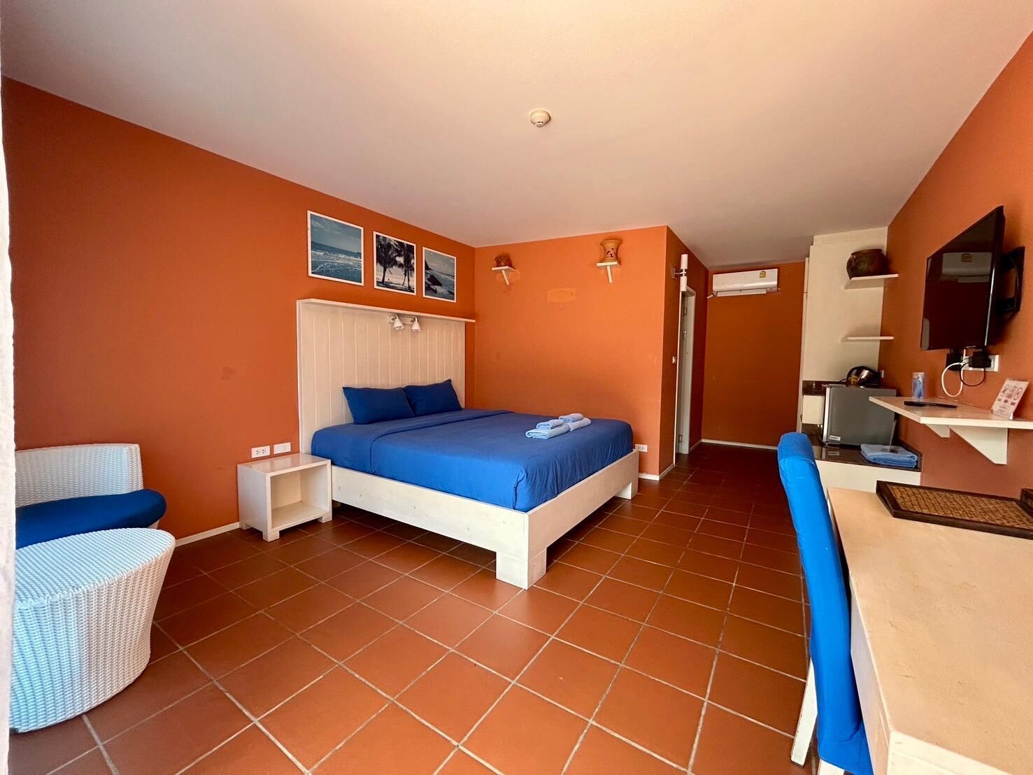 A hotel room with a bed, a desk, a chair, and a TV.