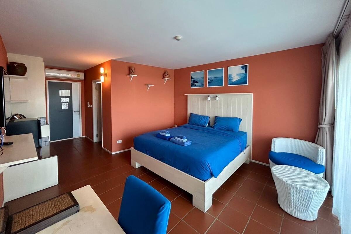 Quarto de hotel com uma cama grande, uma escrivaninha e uma cadeira.