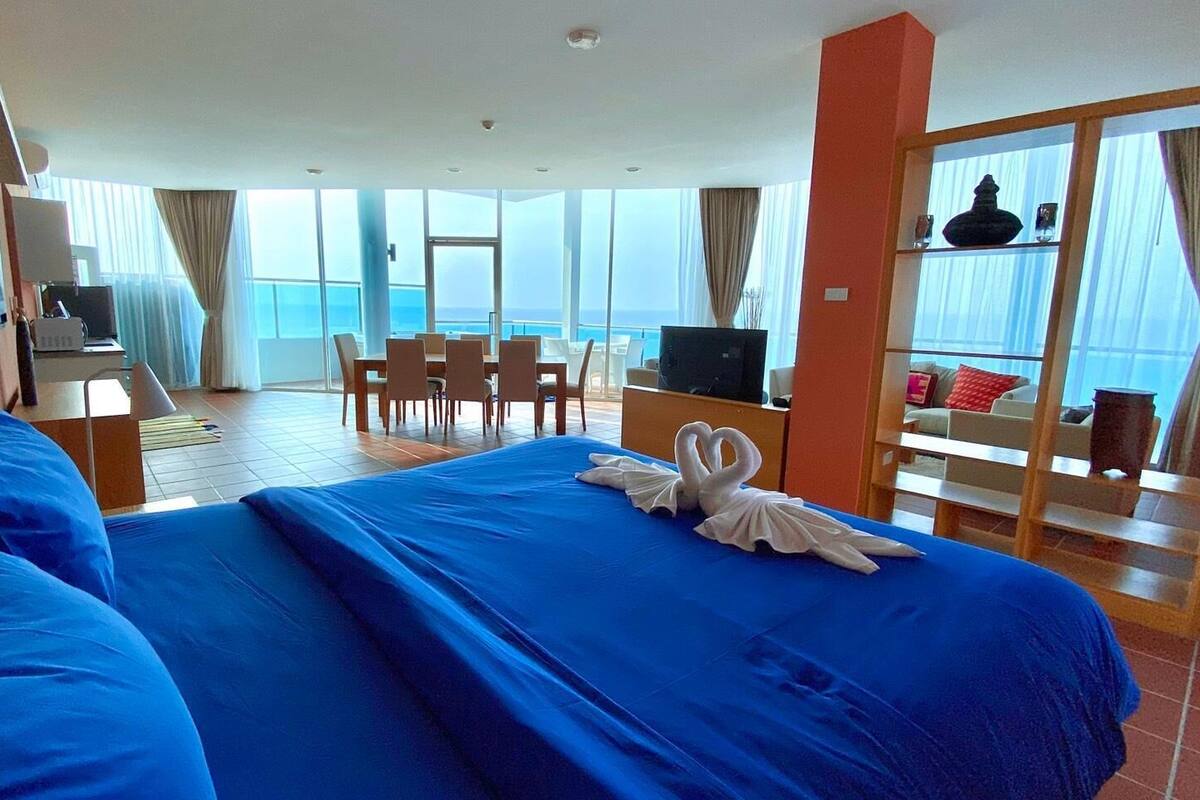 Quarto de hotel com uma cama grande, televisão, secretária e varanda com vista para o mar.