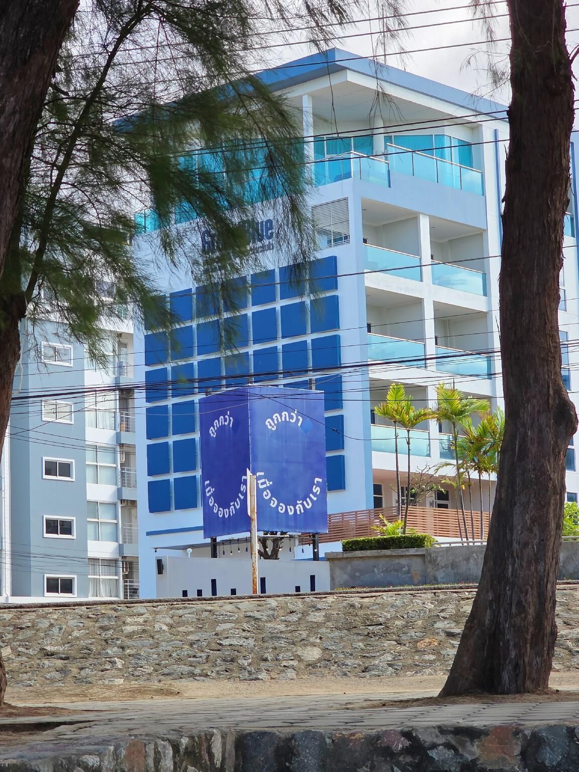 Een modern gebouw met meerdere balkons en een stenen muur op de voorgrond.