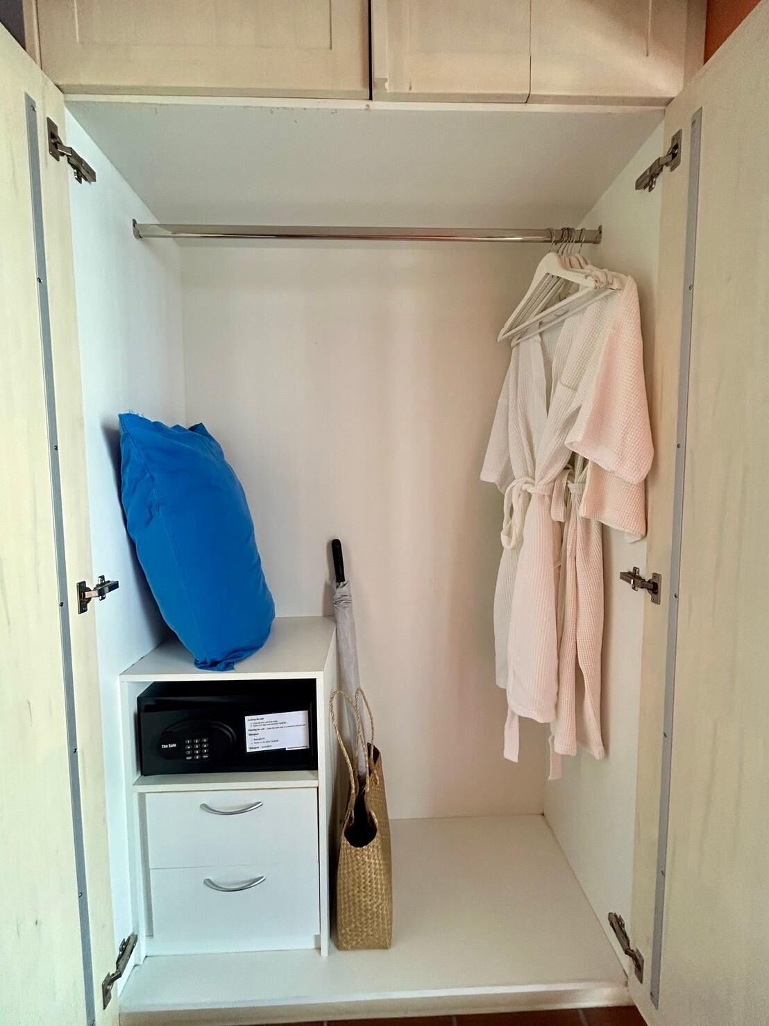 Un armario vestidor con una percha, una almohada azul, un módulo de almacenamiento blanco y un bolso tejido.