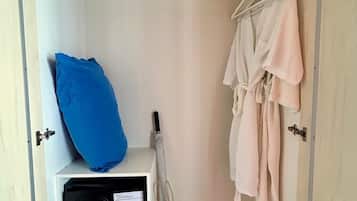 Un armario vestidor con una percha, una almohada azul, un módulo de almacenamiento blanco y un bolso tejido.