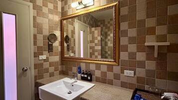 Un baño con un lavamanos blanco, un espejo grande y una pared con azulejos.