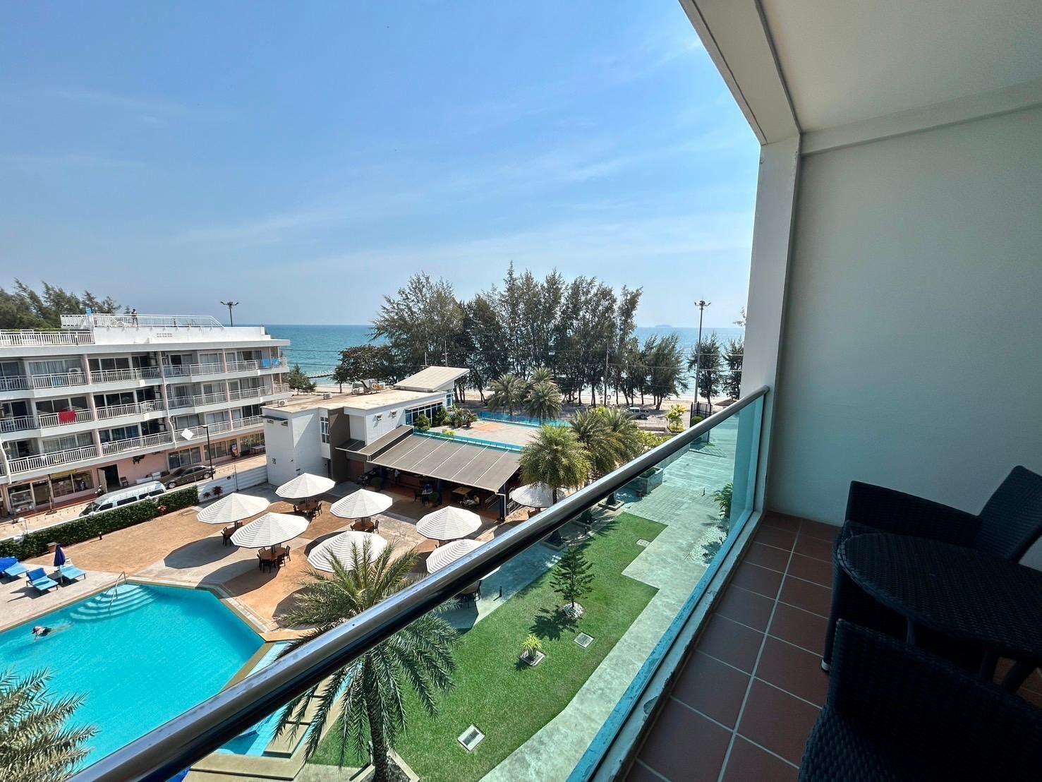 A hotel with a pool, outdoor seating, and a view of the sea.