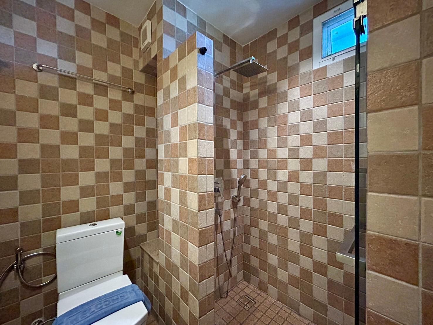 Un baño con paredes de baldosas a cuadros, una ducha y un inodoro.