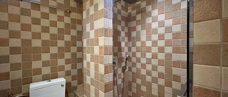 Un baño con paredes de baldosas a cuadros, una ducha y un inodoro.