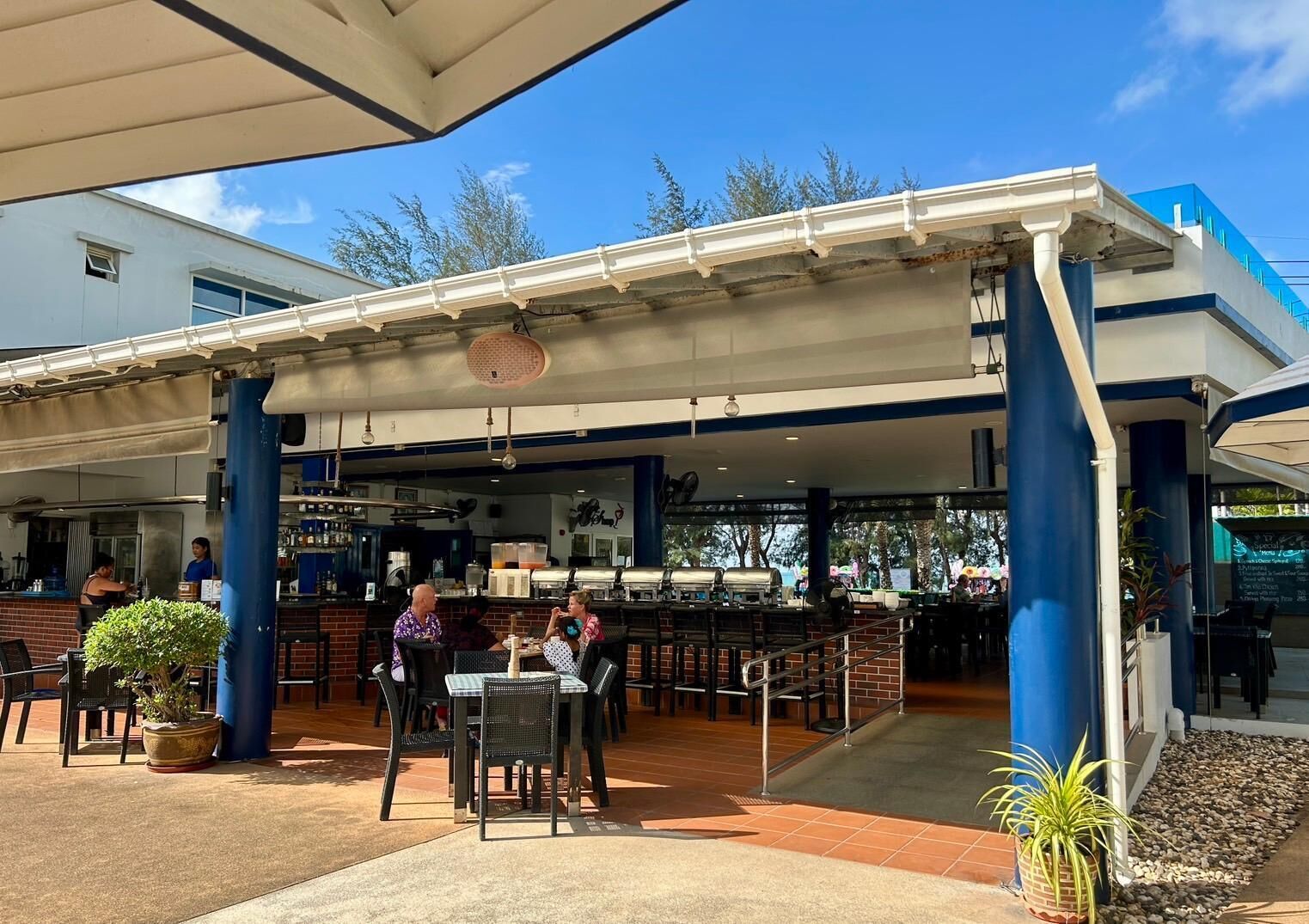 An outdoor seating area with tables and chairs, a bar, and a covered patio.