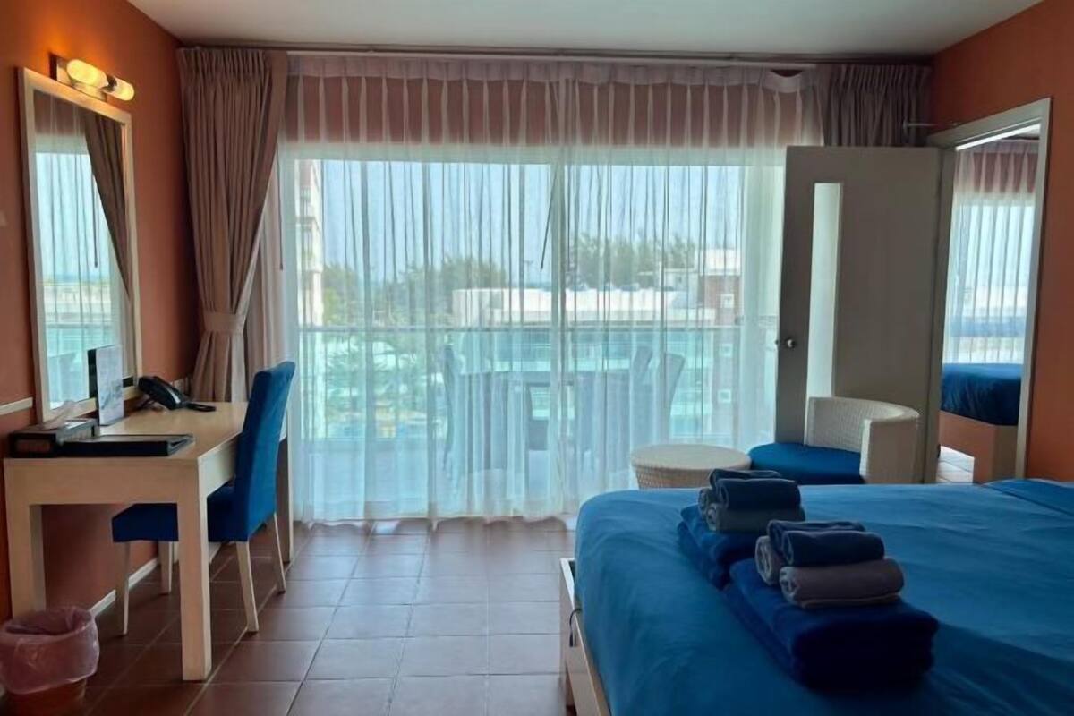 Quarto de hotel com cama, escrivaninha, cadeira, mesa pequena e varanda com vista.