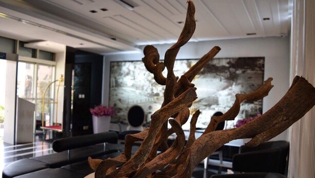 A modern interior with a central art installation of twisted branches, contemporary furniture, and a large abstract painting on the wall. - Crystal Hotel (Amman)