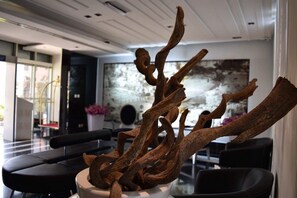 A modern interior with a central art installation of twisted branches, contemporary furniture, and a large abstract painting on the wall.