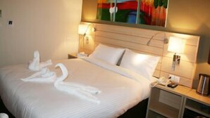 A hotel room with a large bed, two bedside lamps, a painting on the wall, and a telephone on the nightstand. - Crystal Hotel (Amman)