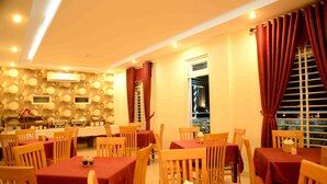 Un comedor con varias mesas y sillas, un muro con diseño y una ventana con cortinas.