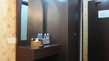 A room with a wooden vanity, a mirror, and a door with a sign.