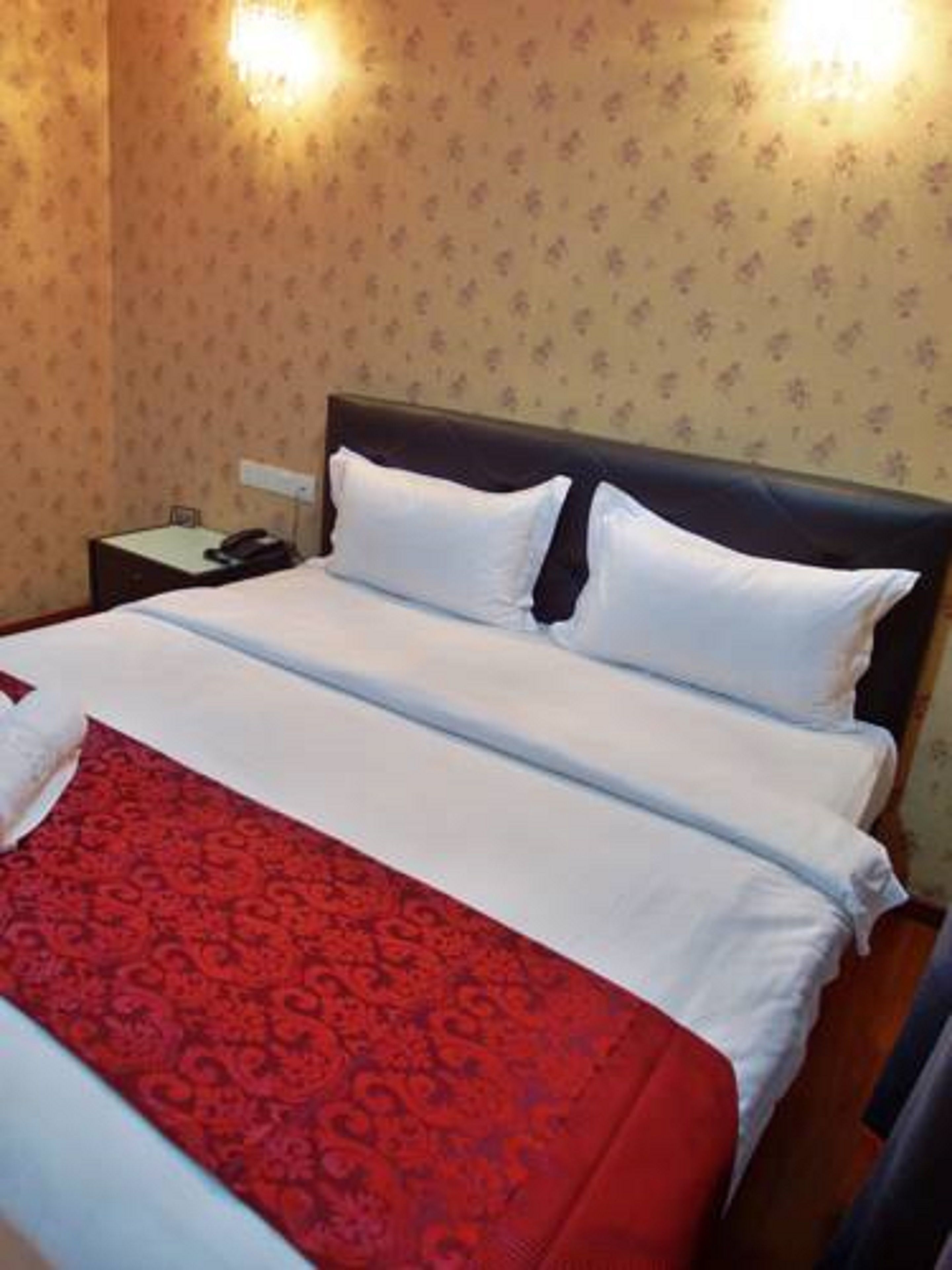 A hotel room with a bed, a nightstand, and a telephone.