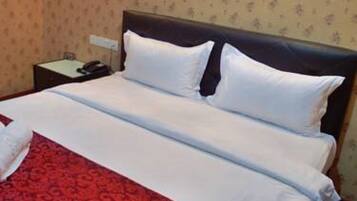 A hotel room with a bed, a nightstand, and a telephone.