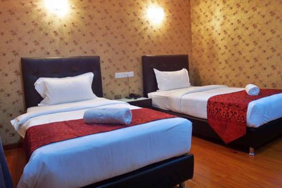 Habitación de hotel con dos camas, cada una con ropa blanca y mantas rojas.