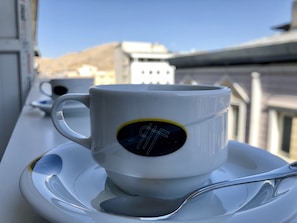 A white cup with a digital display on a saucer and spoon on a balcony. - Hotel Fuat (Van)