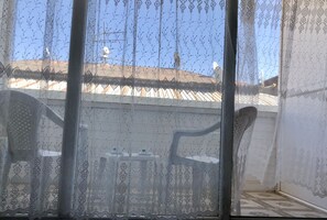 A room with a patterned window blind, a chair, and a view of the outside. - Hotel Fuat (Van)