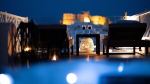 Una terraza con dos sillones de descanso, una mesa con dos copas de vino tinto y un farol decorativo.