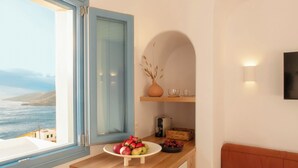 Una cocina con vistas al mar, un frutero, un florero y una cafetera.