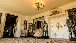 Una habitación amplia con candelabro, un espejo grande y una estatua de caballero.