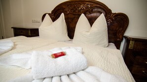 Una cama bien hecha con cabecera de madera, almohadas blancas y una bata doblada sobre la cama.