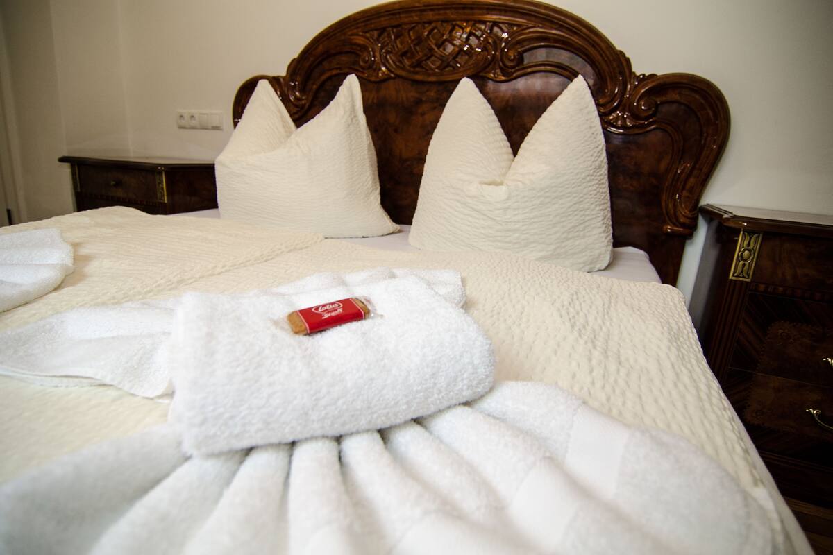 A neatly made bed with a wooden headboard, white pillows, and a folded robe on the bed.