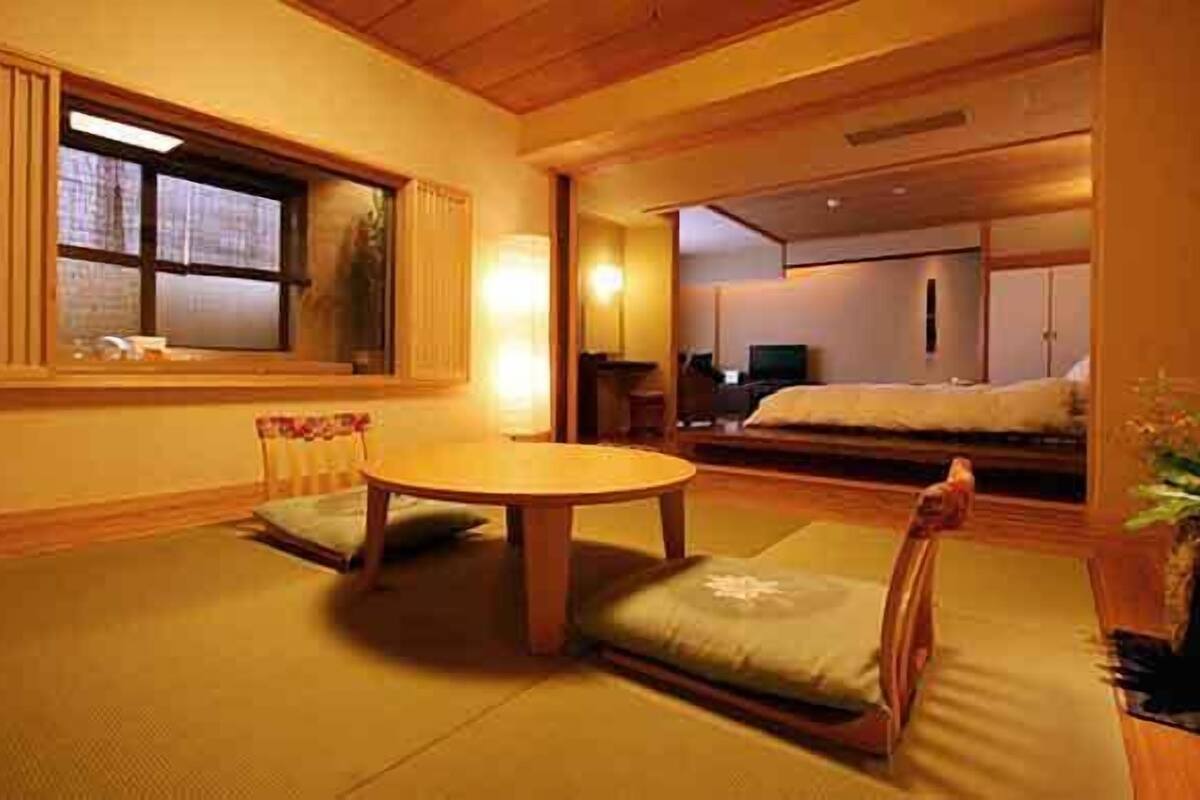 Une pièce de style japonais traditionnel, avec un sol recouvert de tatamis, une petite table basse en bois et un futon servant de lit.