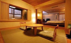 Una tradizionale stanza in stile giapponese con pavimento in tatami, un tavolino di legno e un futon.