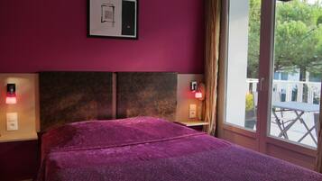 Una habitación con cama, dos lámparas de noche, una ventana con vistas a la vegetación y un interruptor de luz en la pared.