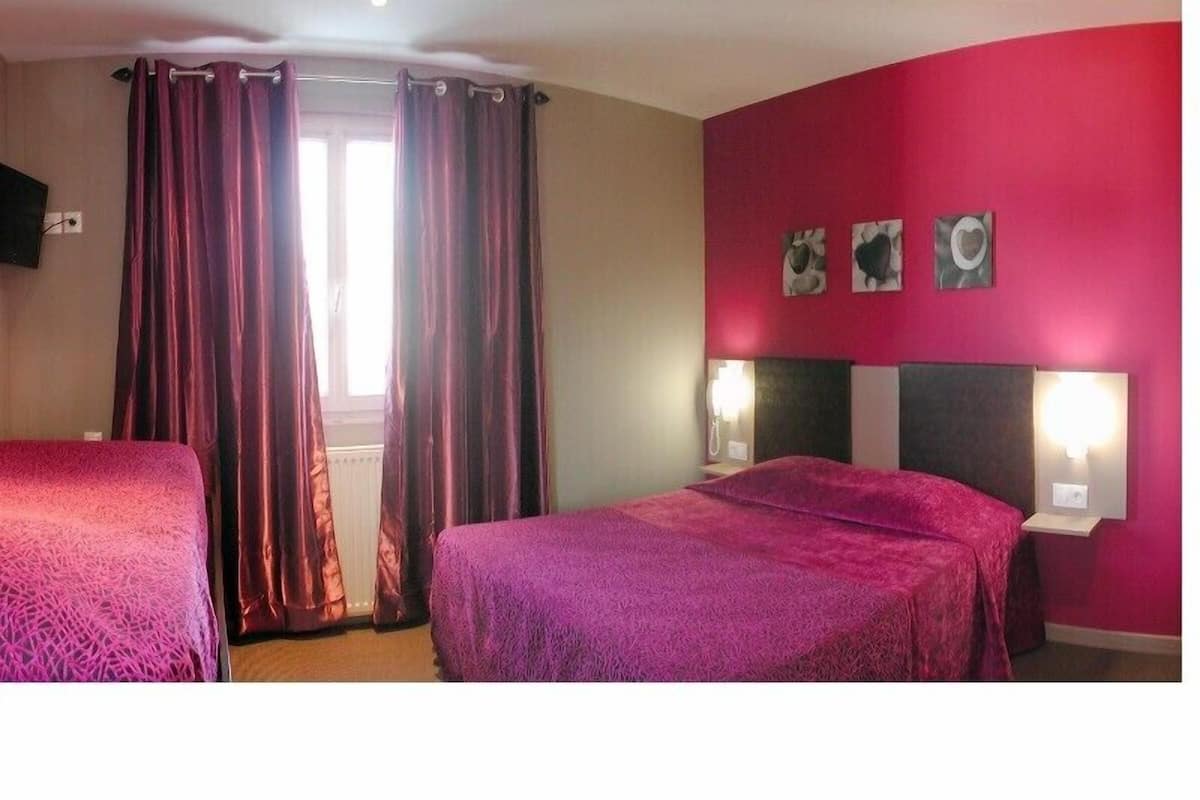 A hotel room with two beds, a window with curtains, and a wall with three decorative items.