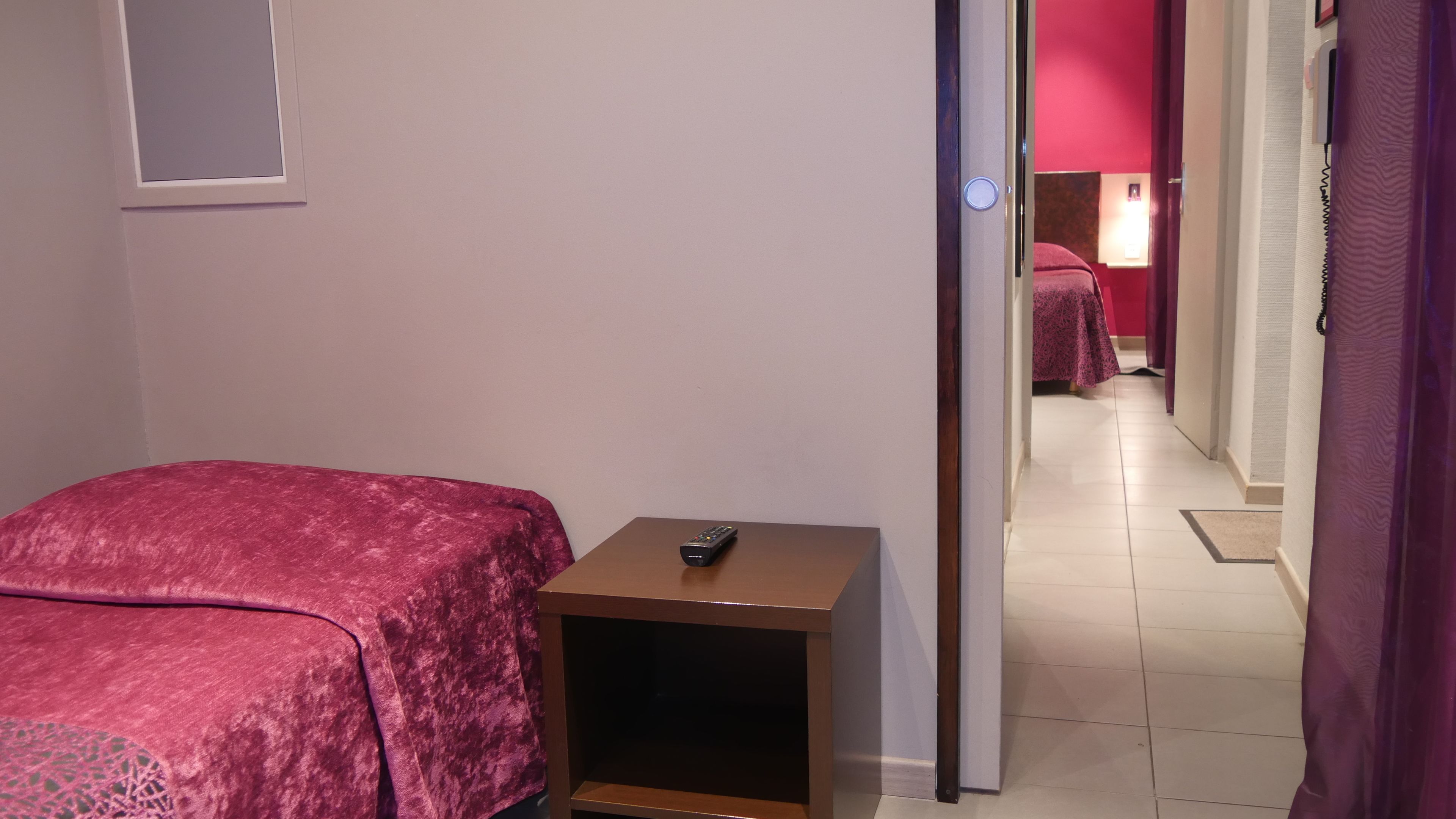 Ein Hotelzimmer mit einem Bett, einem Nachttisch und einer Fernbedienung auf dem Nachttisch.