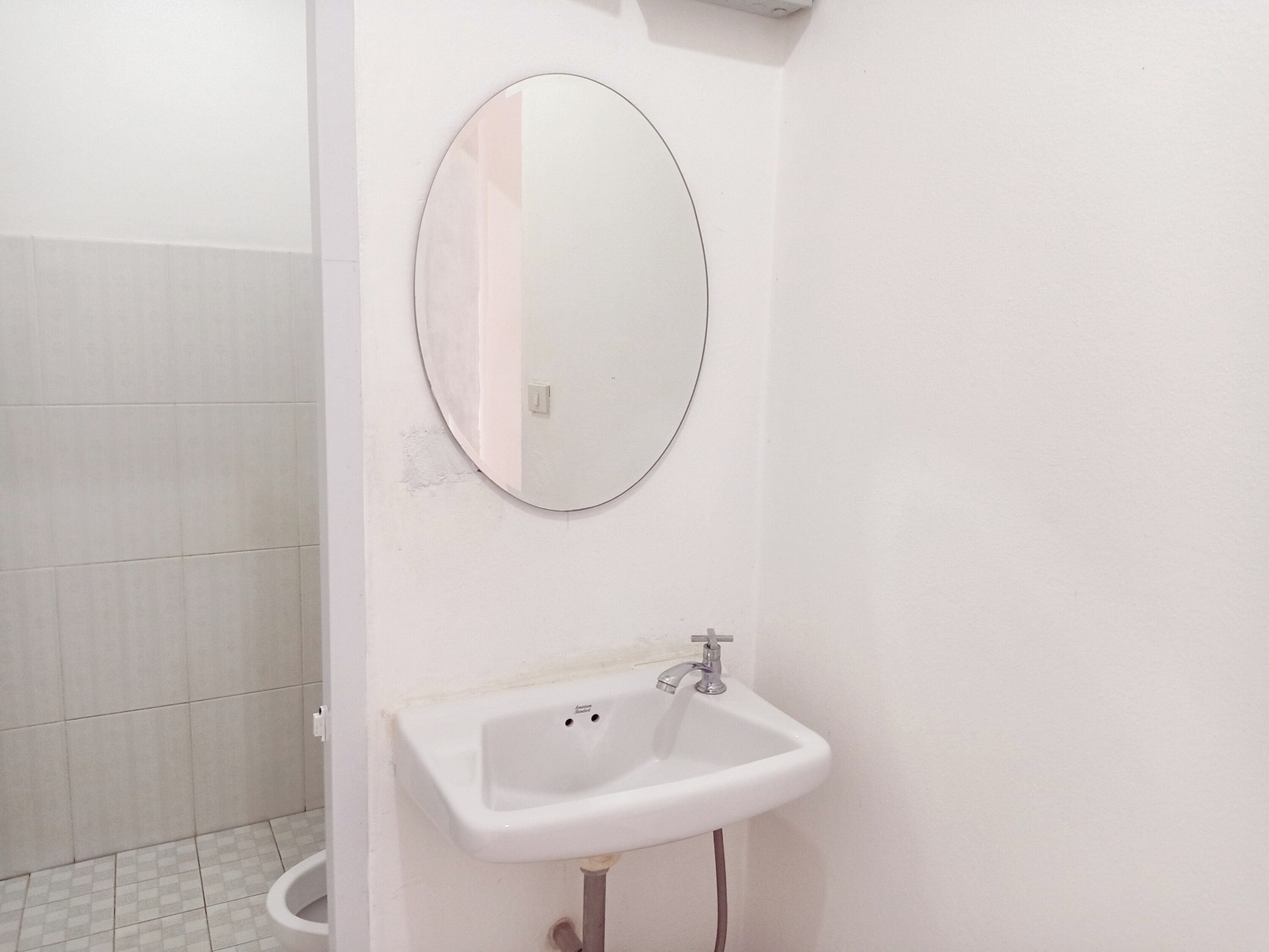 A bathroom with a white sink, a mirror, and a tiled floor.
