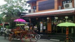 A traditional building with a tiled roof, a horse-drawn carriage, and a signboard outside.