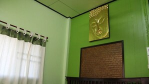 A room with a bed, a curtain, a headboard, and a wall with a textured panel and a framed artwork.
