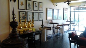 A room with a dining table, chairs, and a decorative lamp. There are framed pictures on the wall and a window with a view outside.