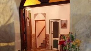 An interior courtyard with a tiled floor, a wooden staircase, and potted plants. - Riad Ksar El Jadida (El Jadida)