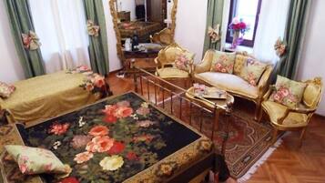 A room with a bed, a sofa, a chair, a mirror, and a small table.