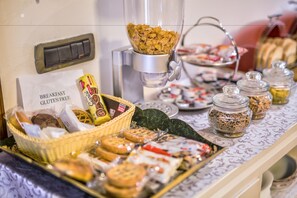 A buffet with various food items, including cookies, pastries, and a sign indicating gluten-free options.