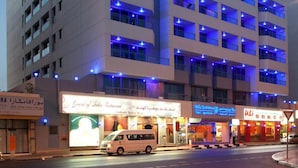 Een meerhoog hotel met verlichte ramen en een bord met 'Hotel of India Restaurant'.