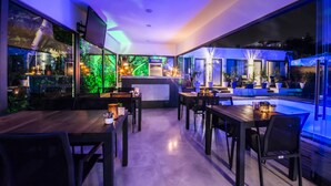 A modern restaurant with a pool area, wooden tables, and chairs. - Eng Group Hotels (Bodrum)