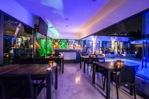 Un restaurante moderno con zona de piscina, mesas y sillas de madera.