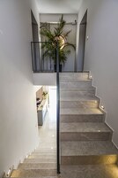 Una escalera de diseño moderno, con barandilla de metal y una planta en maceta en la parte superior.