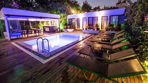 A modern outdoor pool area with a wooden deck, built-in seating, and a small pool with a ladder. - Eng Group Hotels (Bodrum)