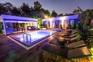 A modern outdoor pool area with a wooden deck, built-in seating, and a small pool with a ladder. - Eng Group Hotels (Bodrum)