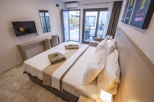 Habitación de hotel con cama, televisión de pantalla plana en la pared, ventana y puerta que da a un balcón.